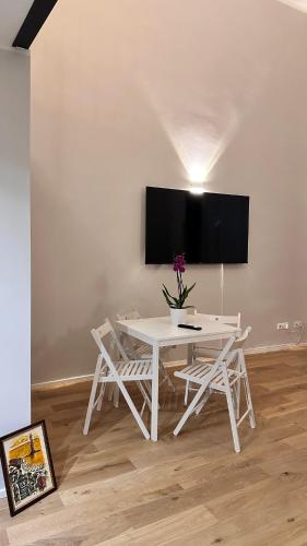 a white table with two chairs and a tv on a wall at Centro Storico Caruggi 2min Acquario Pellicceria Superior Loft Palazzo Rolli in Genova