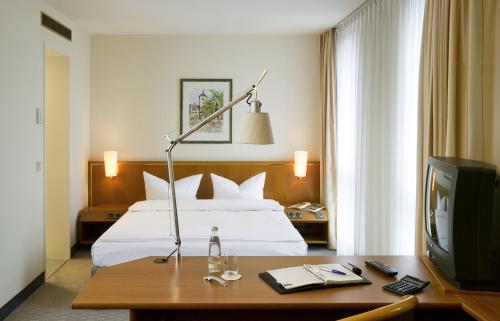 a hotel room with a bed and a desk with a television at Novotel Freiburg am Konzerthaus in Freiburg im Breisgau