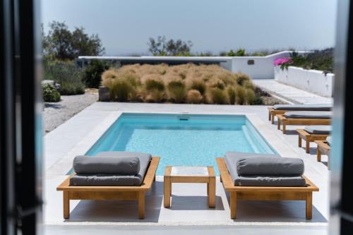 a swimming pool with chaise lounge chairs and a table at Philosophia Luxury Villa in Megalokhori