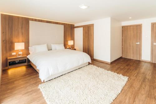 a bedroom with a white bed and a white rug at Hotel Miraflores in Ambato