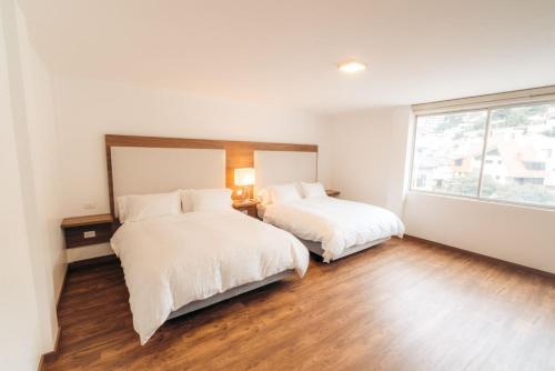 a bedroom with two beds and a large window at Hotel Miraflores in Ambato