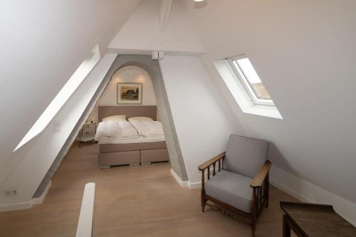 sypialnia na poddaszu z łóżkiem i krzesłem w obiekcie Budersandhaus w mieście Hörnum