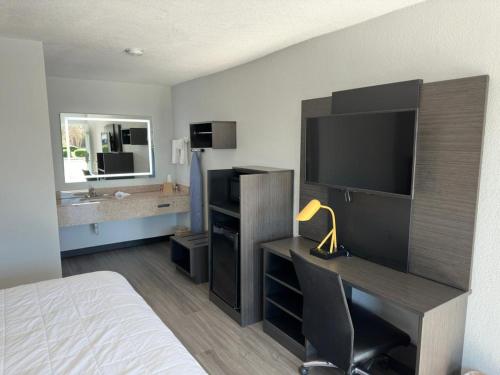 a bedroom with a bed and a desk with a television at Baymont by Wyndham Rock Hill in Rock Hill