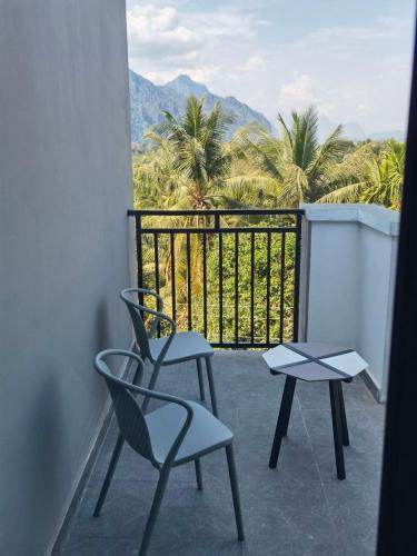 a balcony with two chairs and a table and palm trees at ChanthaSouk Vang Vieng Entire Villa in Vang Vieng