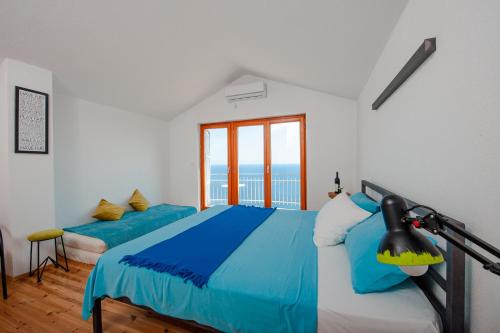 ブドヴァにあるSunSeoce Apartmentsのベッドが2つと大きな窓がある寝室