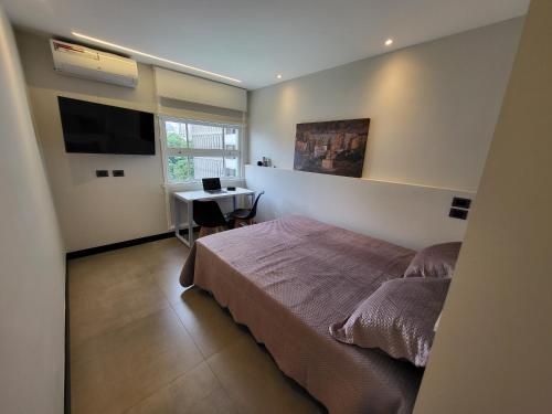 Schlafzimmer mit einem Bett, einem Schreibtisch und einem TV in der Unterkunft Studio Silvia in São Paulo
