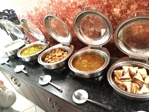 een buffet met veel verschillende soorten eten in pannen bij BRINJAL HOTELS, HARIDWAR in Haridwār