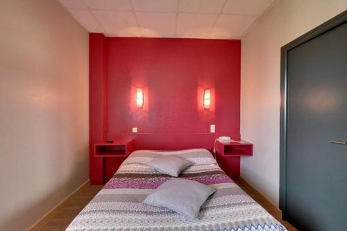 - une chambre dotée d'un mur rouge et d'un lit avec deux oreillers dans l'établissement Logis Auberge des Vieux Chenes, à Malemort-sur-Corrèze