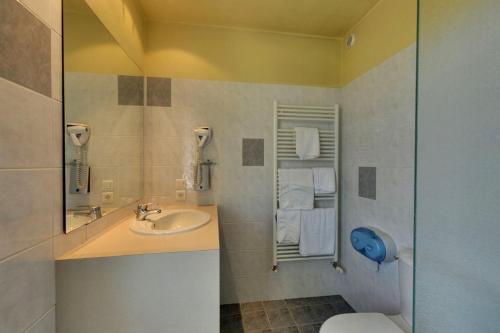 La salle de bains est pourvue d'un lavabo et de toilettes. dans l'établissement Logis Auberge des Vieux Chenes, à Malemort-sur-Corrèze
