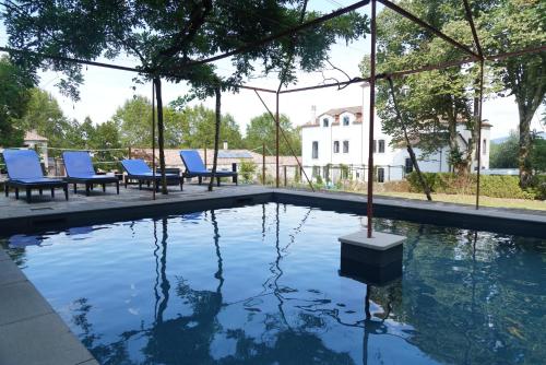 a swimming pool with blue chairs next to a building at Quinta do Areal in Lousã