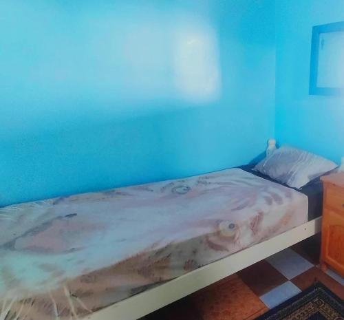 a bed in a room with a blue wall at Auberge Maison Diyani in Sidi Ifni