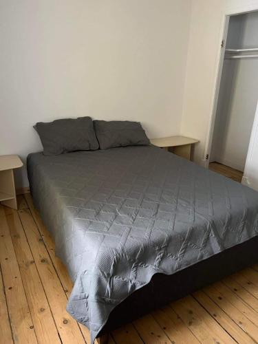 a bed with a gray comforter in a bedroom at Résidences touristiques l’Abris in LʼAnse-Saint-Jean