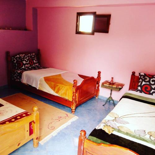 a bedroom with two beds and a table with a window at Auberge Maison Diyani in Sidi Ifni