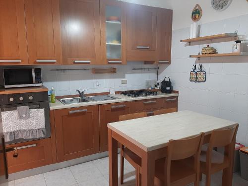 a kitchen with wooden cabinets and a sink and a table at Milano Linate Airport Apartment in Peschiera Borromeo