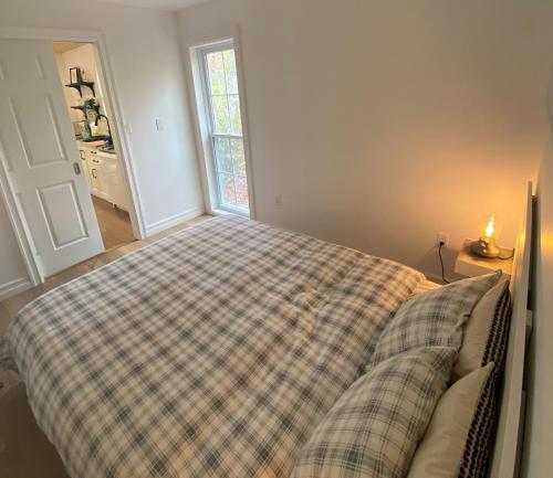 a bedroom with a bed with a plaid blanket at Bear Cabin - Cozy Forest Retreat nearby Lake in East Kemptville