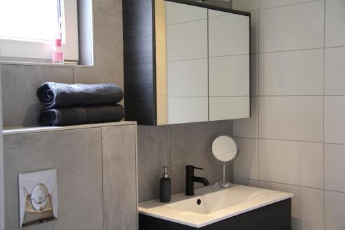 La salle de bains est pourvue d'un lavabo, d'un miroir et de serviettes. dans l'établissement Bed & Breakfast Bij de Wilg, à Laren