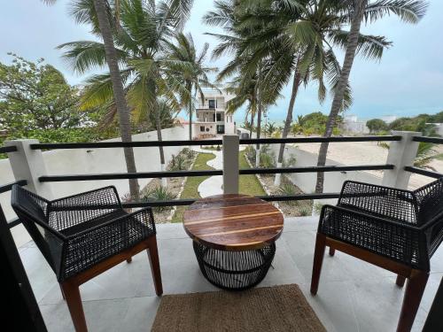 two chairs and a table on a balcony with palm trees at Playanet in Chelem