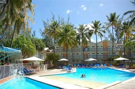 una grande piscina con palme e un hotel di NOUVEAUTÉ CLÉ EN MAIN - L'EDEN - STUDIO HOTEL CARAYOU: BAR, PISCINE, PLAGES a Les Trois-Îlets