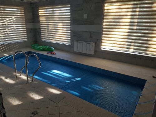 a swimming pool in a room with two windows at Mežnoras holiday house in Šņores