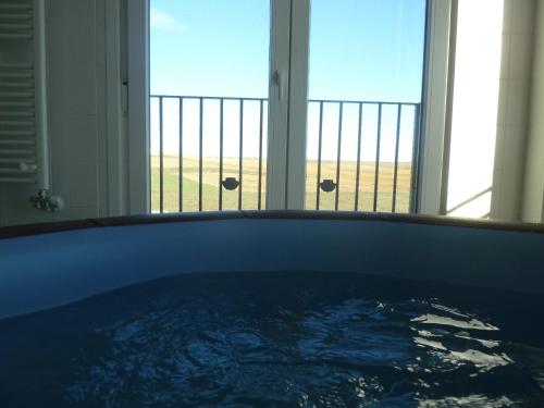 a tub in a bathroom with a view of the ocean at Hostal Moratinos in Moratinos