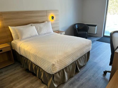 a bedroom with a large bed with a desk and a chair at Econo Lodge Airport Quebec in Quebec City