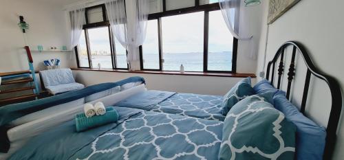 - une chambre avec un lit bleu et une vue sur l'océan dans l'établissement Salema casa de playa en San Cristobal, à Las Palmas de Gran Canaria