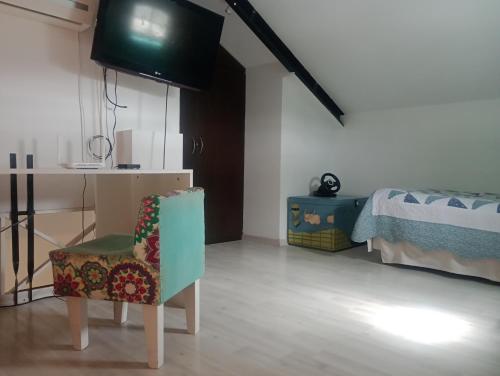Habitación con TV, silla y cama. en Ayres del Cerro en San Salvador de Jujuy