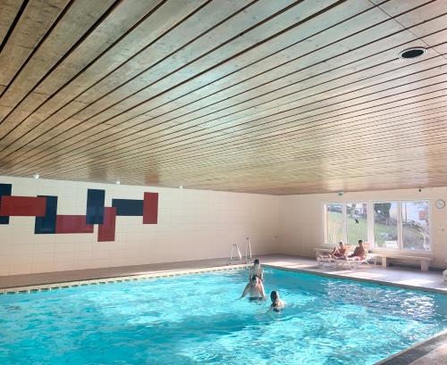 a swimming pool with two people in the water at FeWo Alpenwiese mit Hallenbad&Sauna in Missen-Wilhams