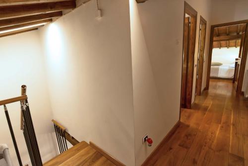 a hallway with a white wall and wooden floors at Gattaia Apartments with swimming pool in Gattaia