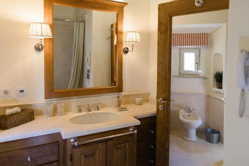 a bathroom with a sink and a toilet and a mirror at Suites at the Villas by Quinta da Bella Vista in Sintra