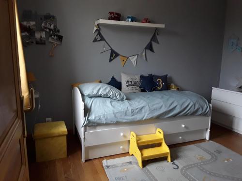 a childs bedroom with a bed and a yellow stool at Chaleureuse fermette à proximité du circuit des 24h du MANS in Ruaudin
