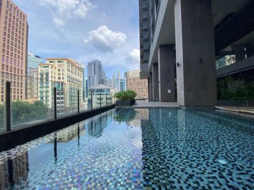 een zwembad in een gebouw met een skyline van de stad bij Anggun Residence Walking distance 5-10mins to Sogo Chow Kit Monorail and LRT station by Juststay in Kuala Lumpur