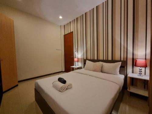 1 dormitorio con 1 cama blanca y 2 zapatillas en ChinJu PoolVilla en Jomtien Beach