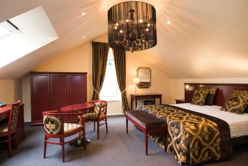 a bedroom with a bed and a desk and a chandelier at Hof de Draeck Bed & Breakfast in Teuven