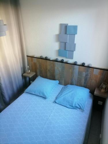 - un lit avec des oreillers bleus et une tête de lit en bois dans l'établissement plage du Môle, au Cap d'Agde