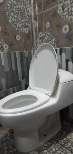 Un inodoro blanco con la tapa en el baño en Marselino Bacpacker's Room, en Bajawa