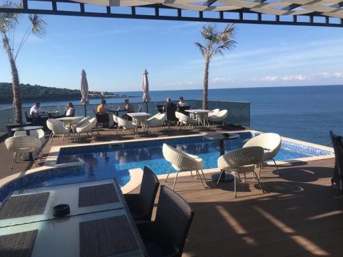 a swimming pool with tables and chairs and the ocean at Apart Lux Beciragic in Dobra Voda