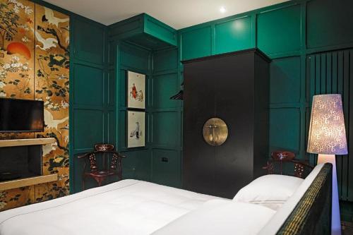 a bedroom with green walls and a bed and a tv at Gileston Manor-Self catering in Saint Athans