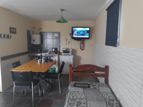 a small kitchen with a table and a television on the wall at Veredas al sol puerto piramides in Puerto Pirámides