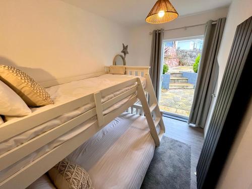 een slaapkamer met 2 stapelbedden en een raam bij Ingledene in Brixham