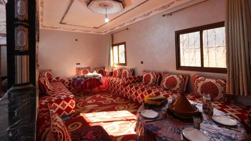 a living room with red couches and a table at Dar Arghen Family Lodge in Imlil