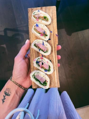 a person holding up four sandwiches on a cutting board at Hotel - Restaurant Soleo in Krumpendorf am Wörthersee