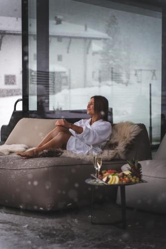 a woman sitting on a couch in a living room at Alpinhotel Berghaus spa in Tux