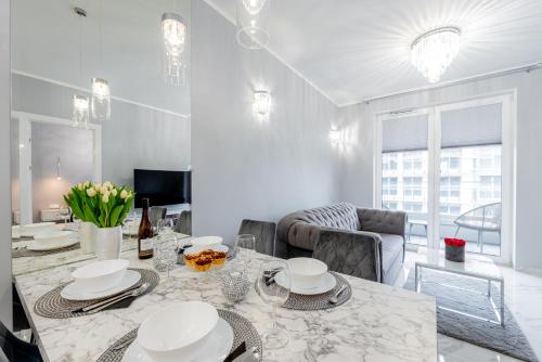 a dining room with a table and a couch at Unique Baltic Apartments - Apartament z garażem in Kołobrzeg