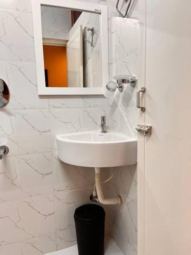 a white bathroom with a sink and a mirror at Izi Airport Stay in Chennai