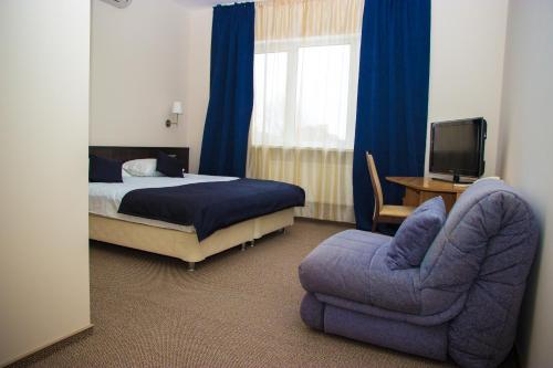 1 dormitorio con 1 cama, 1 silla y TV en Meridian Domodedovo, en Domodedovo