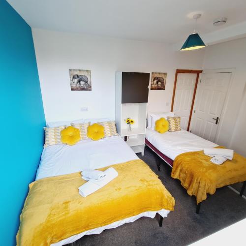 2 bedden in een kamer met gele kussens bij Sheridan House I Long or Short Stay I Special Rate Available in Derby