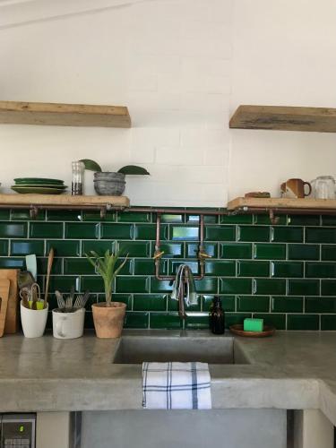 a kitchen with a sink and a green tiled wall at Urban Plett in Plettenberg Bay