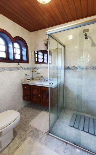 a bathroom with a glass shower and a toilet at Pousada Casa dos Sonhos in Campos do Jordão