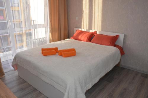 a bedroom with a bed with two orange pillows on it at Студия №1 LifeHouseAlmaty в ЖК Теремки-2 in Almaty